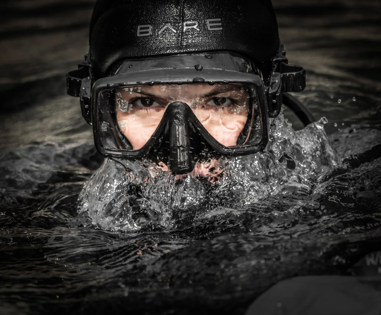 Male diver surfacing in a black single-lens scuba diving mask and a BARE hood