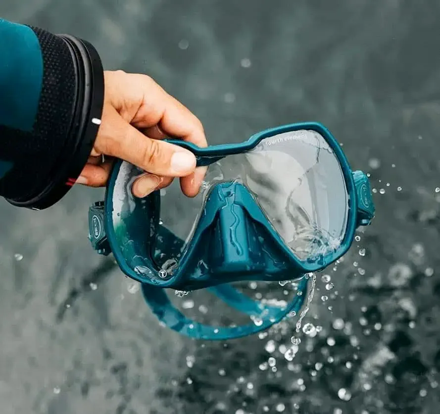 Fourth Element Seeker dive mask with a teal frame being lifted out of the water