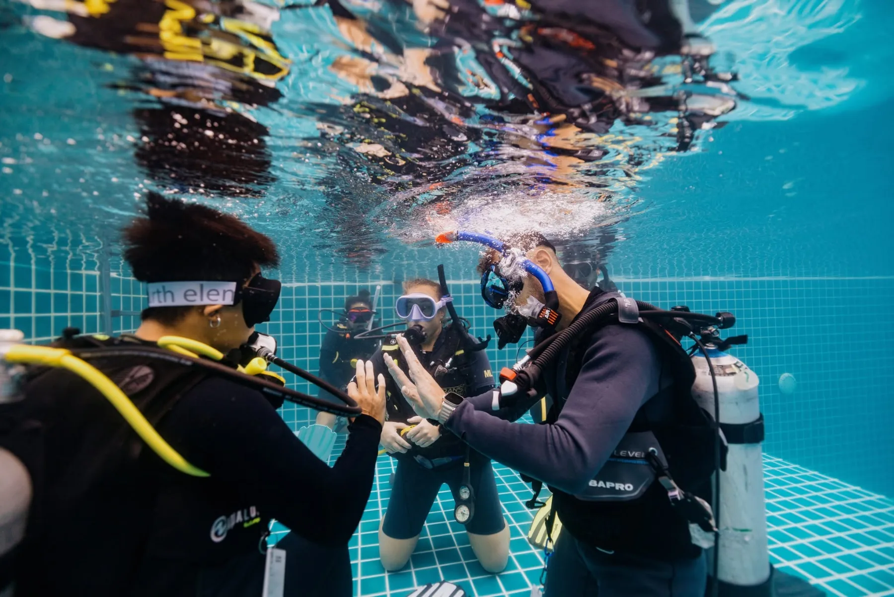 instructor demonstrating a hand signal to a student during a pool training session