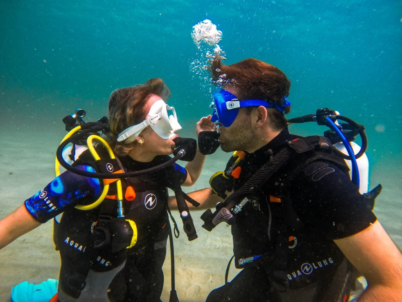 two divers face to face underwater practicing a regulator recovery skill