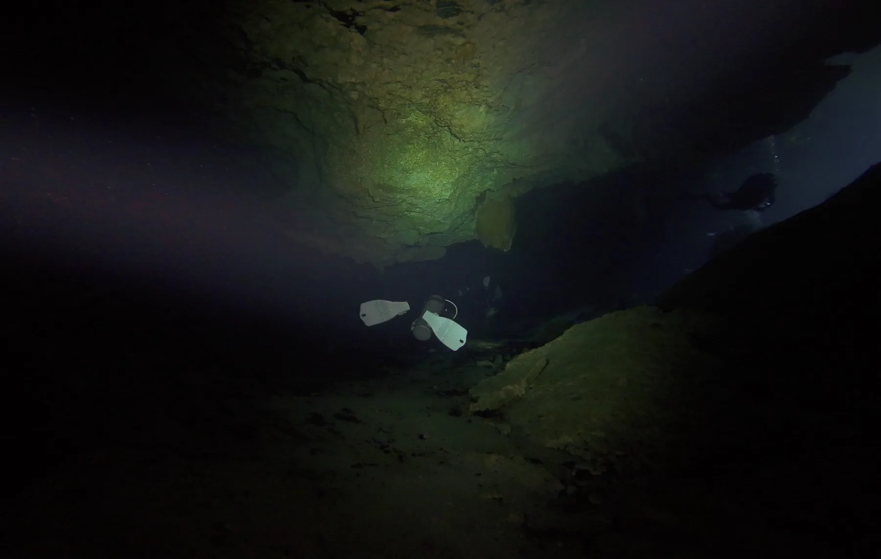 A diver's silhouette in a dark cenote cavern in Mexico