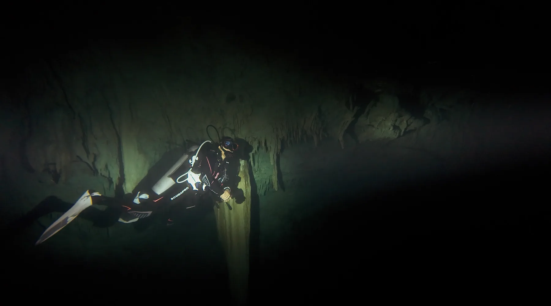 A scuba diver next to a rock formation inside a Mexican cenote