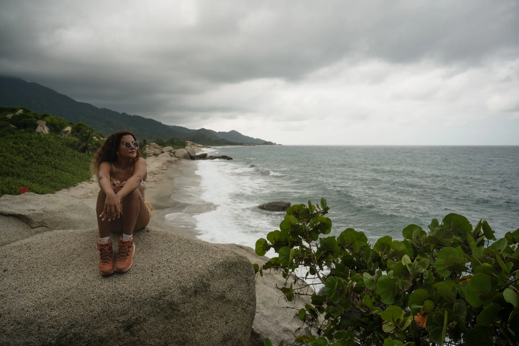 Caro Santamaria sitting on the rocks above a beach in Tayrona National Park, Santa Marta