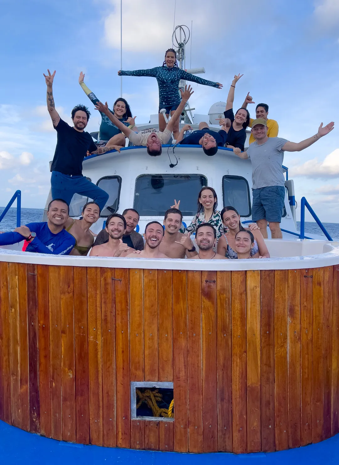 The DivingLife trip group on the back deck of the Sea Wolf, sixteen divers smiling for a sunset group photo after the expedition.