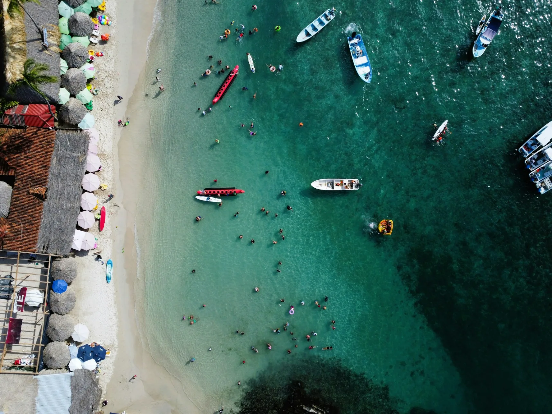 beach destination packed with tourist in the ocean andtour boats around