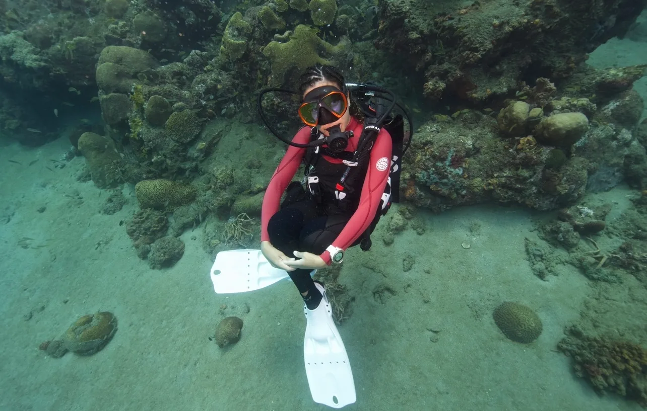 female scuba diver at the reef wearing pink wetsuit and white fins