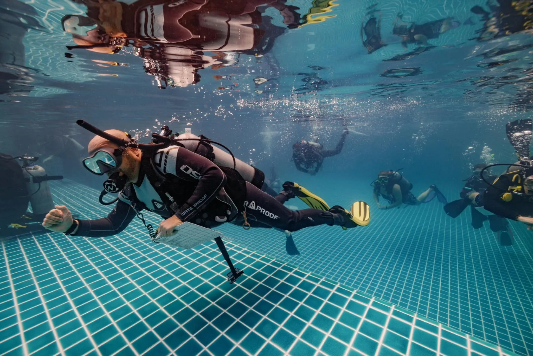 group of scuba divers in a confined session in a pool during padi open water course certification 