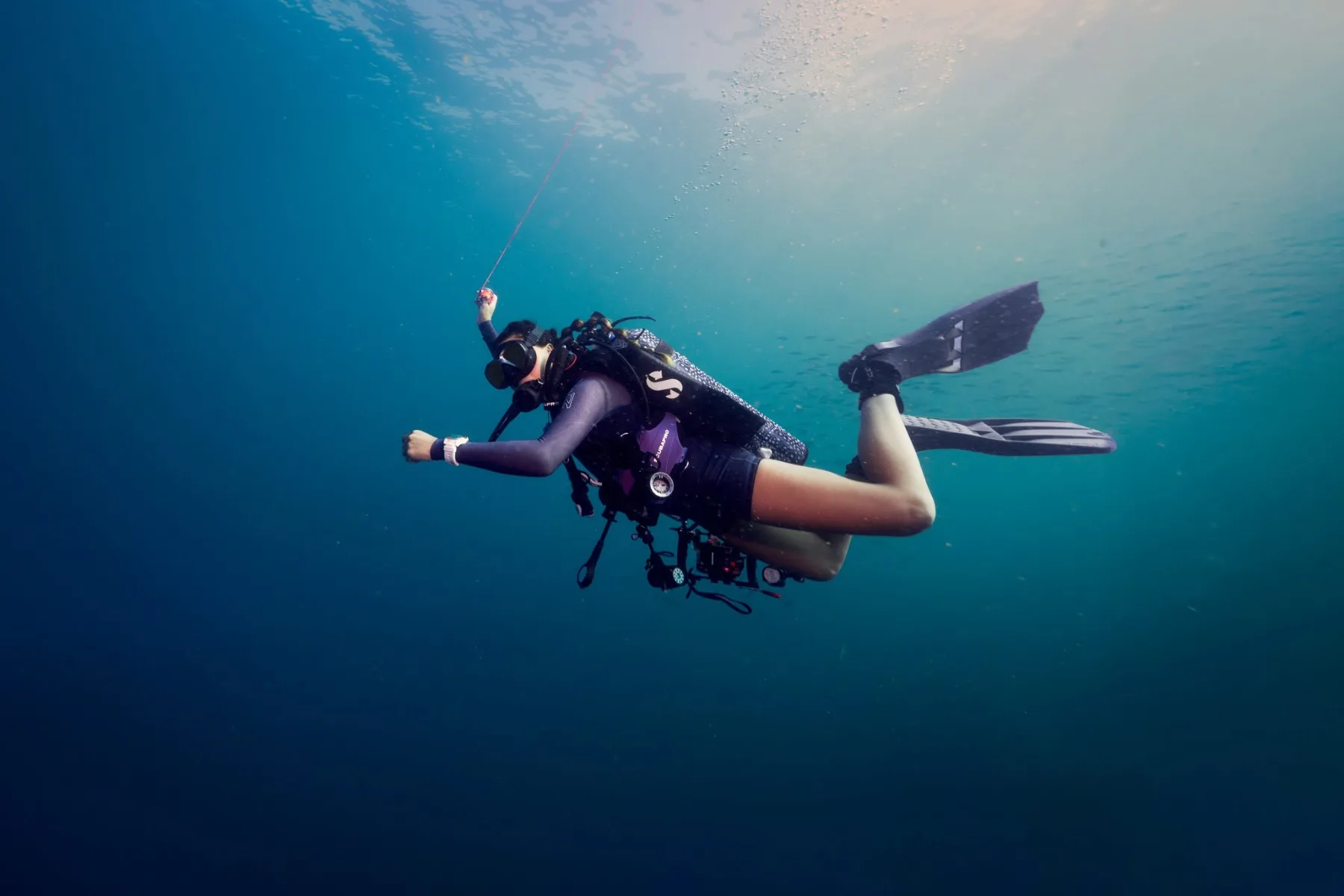 Female scuba diver swimming underwater in clear blue water