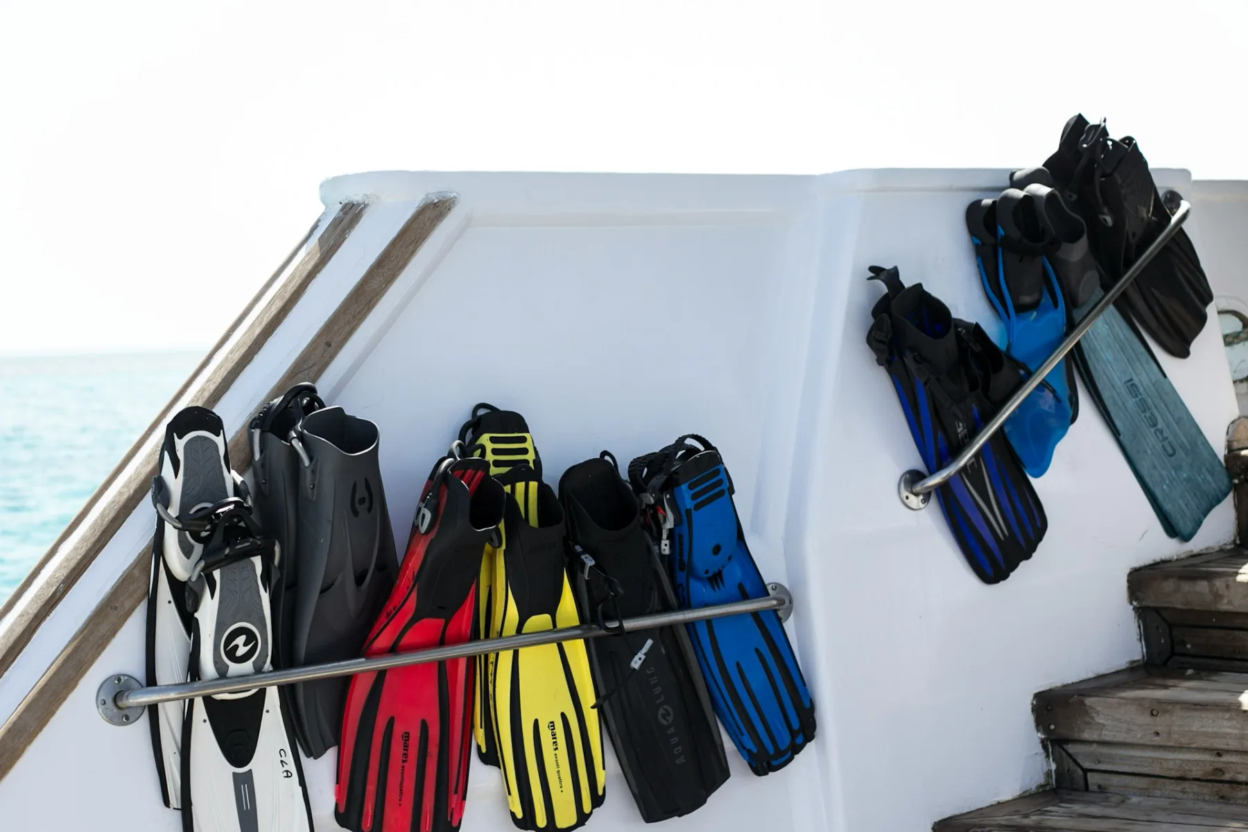 scuba diving fins of different styles and colors hanging on a dive boat