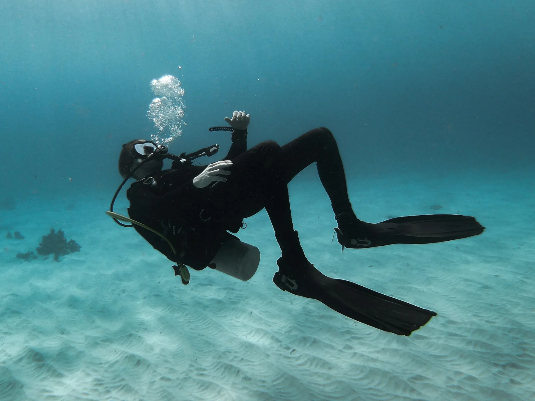 scuba diver wearing all black gear upside down practicing neutral buoyancy