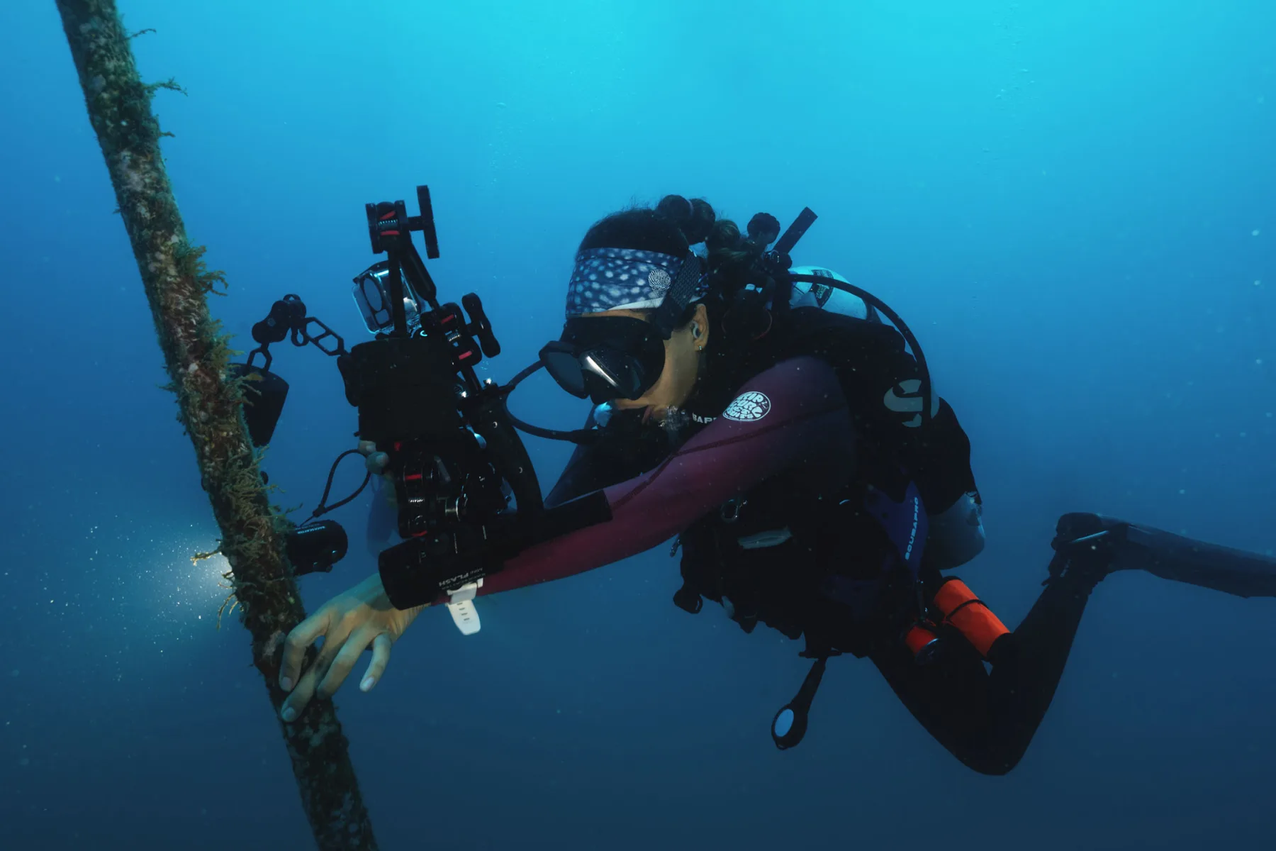 buza sosteniendo una cámara submarina sobre un naufragio