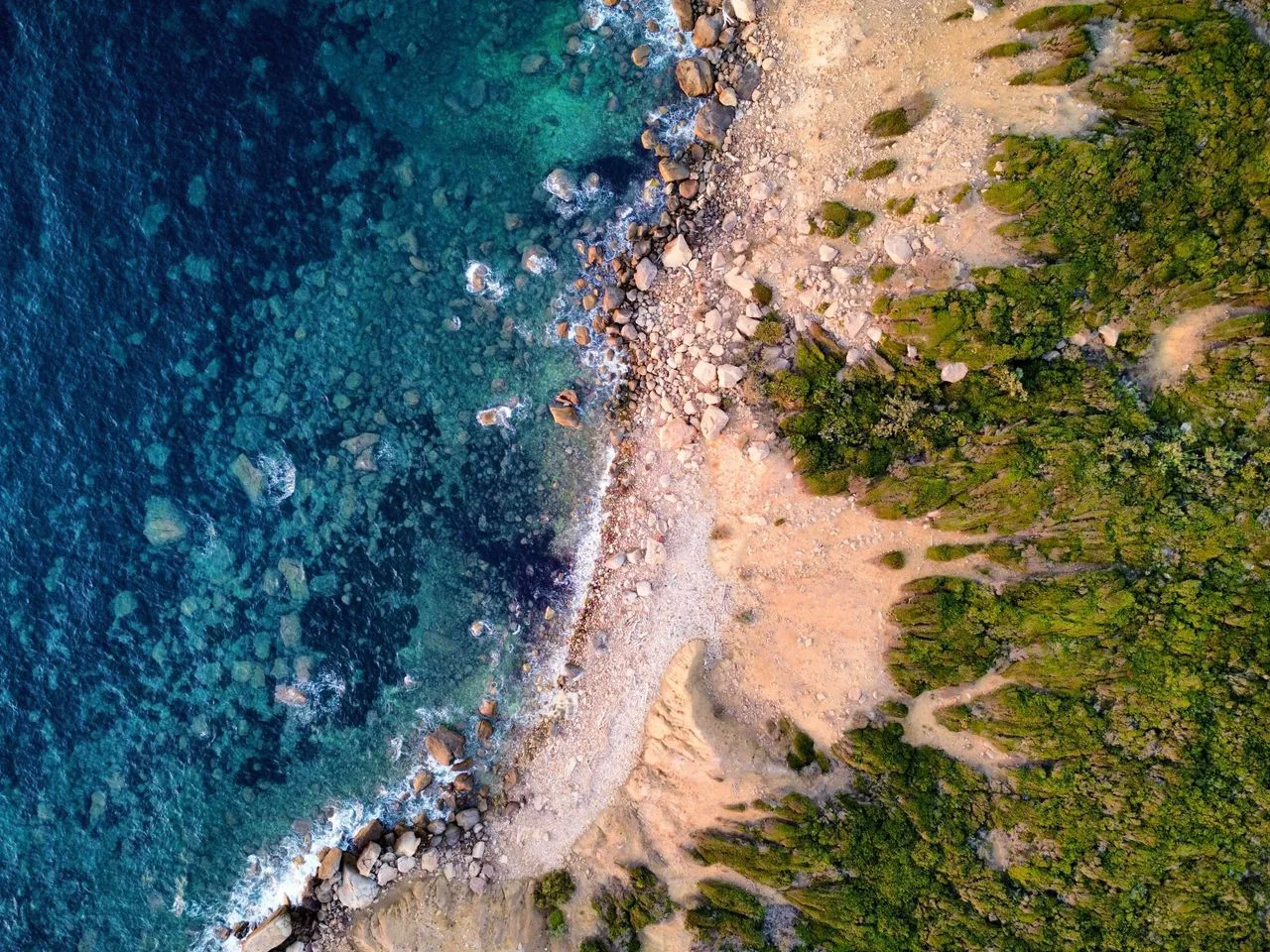 aerial view of coastline, showcasing lush greenery and turquoise waters.