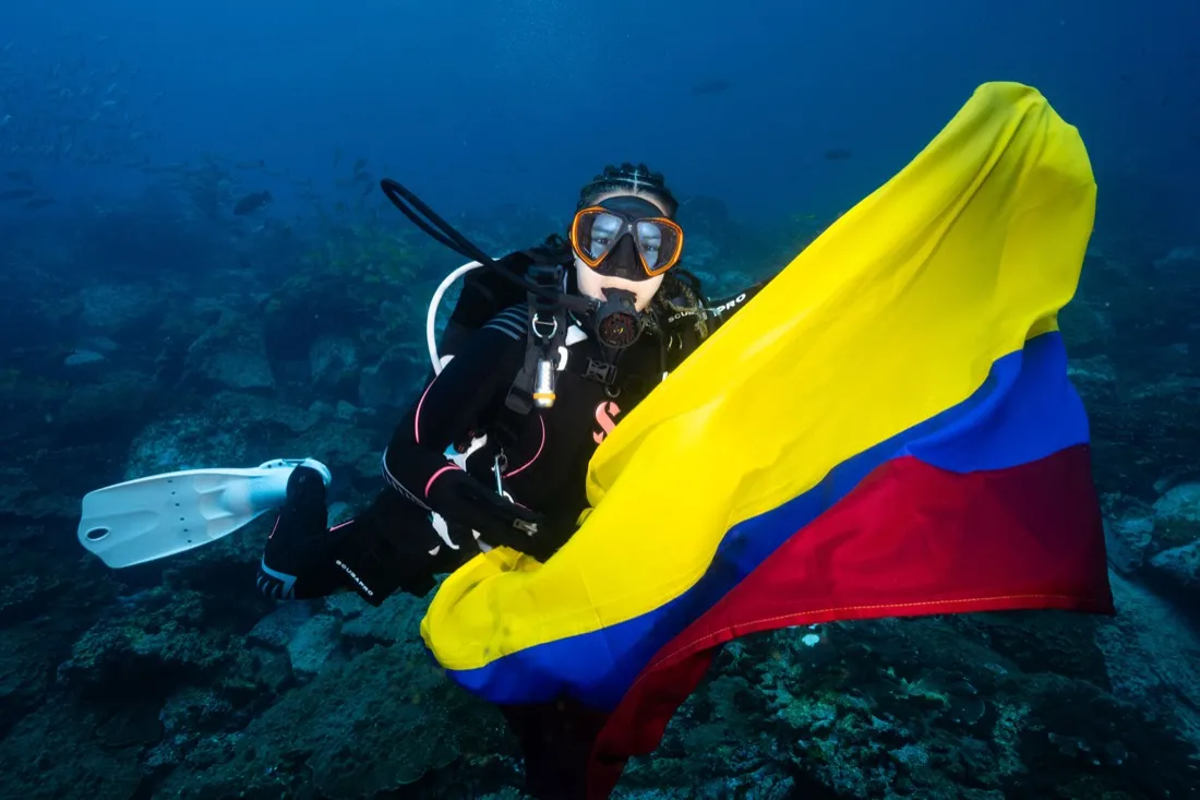 Caro Santamaria scuba diving with the Colombian flag at Malpelo